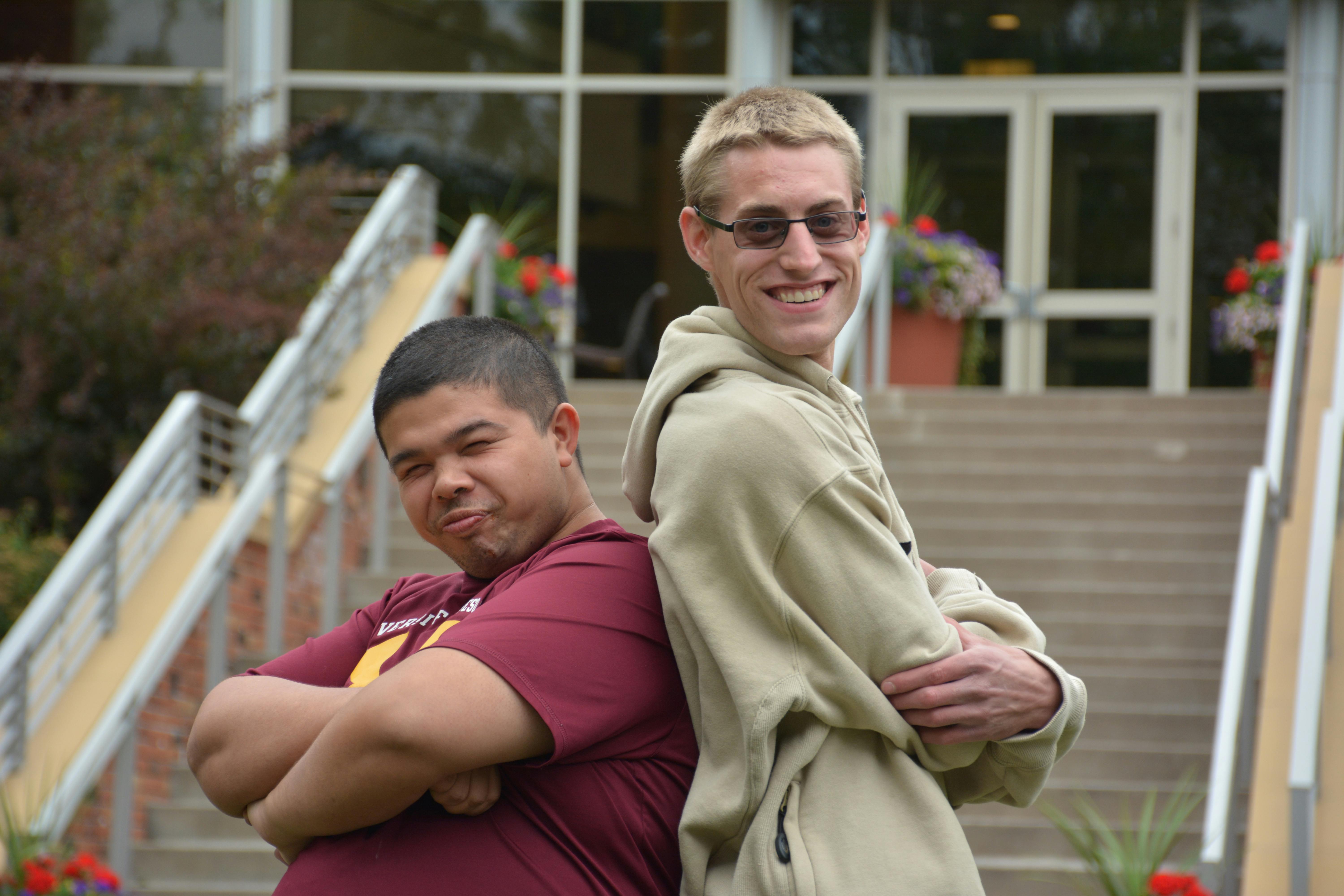 Two smiling students standing back to back.