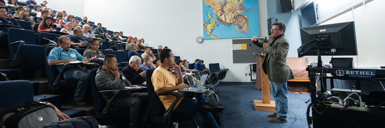 Dr. Juan Hernandez speaks to Hispanic pastors and leaders in a full lecture hall. 