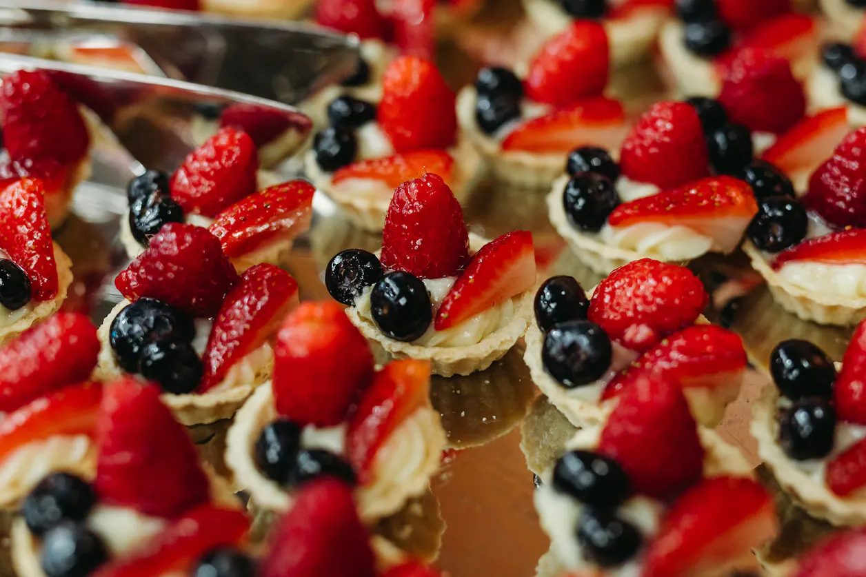 Fruit tarts topped with strawberries, raspberries, and blueberries.