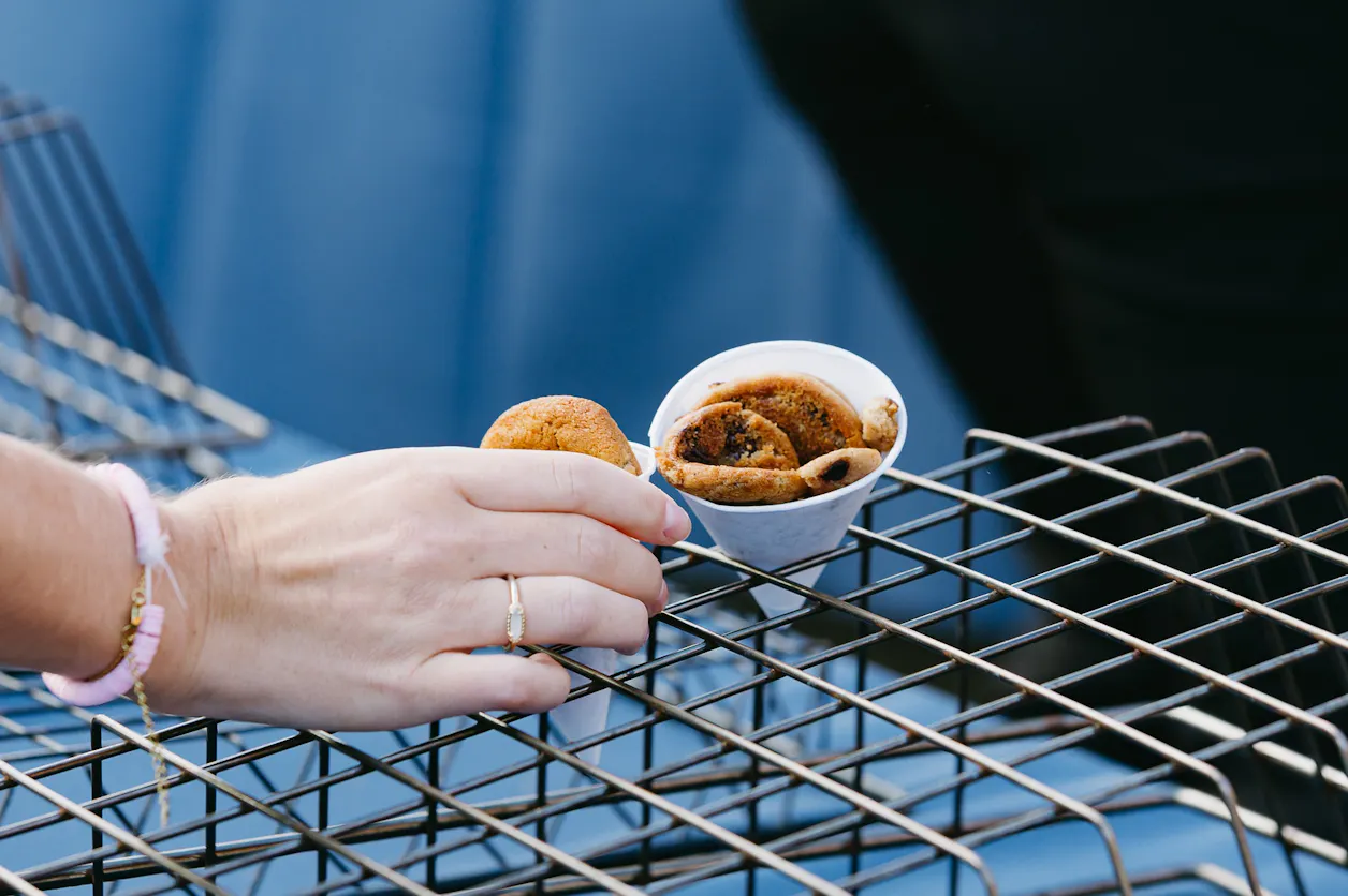Person takes a small cup of cookies from a serving rack.
