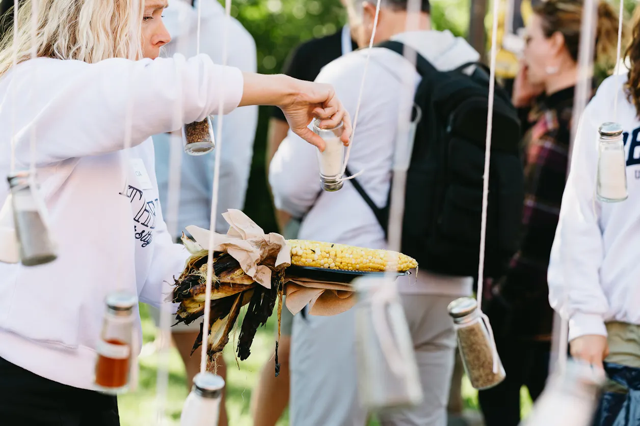 Guest seasons an ear of corn at an outdoor event.
