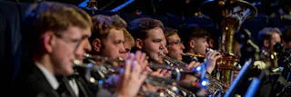 Trumpet section in focus, playing with an orchestra.