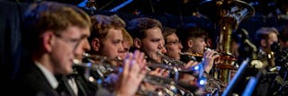 Trumpet section in focus, playing with an orchestra.