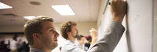 Two men working on a problem on the board