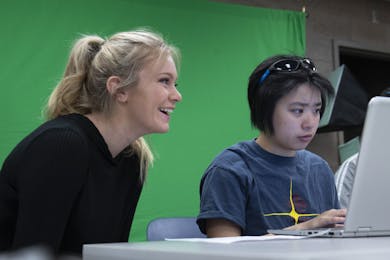 Two students work together on a laptop in the library makerspace.
