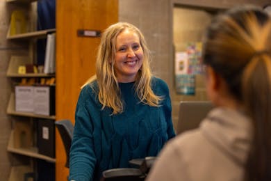 Smiling librarian chats with a student.