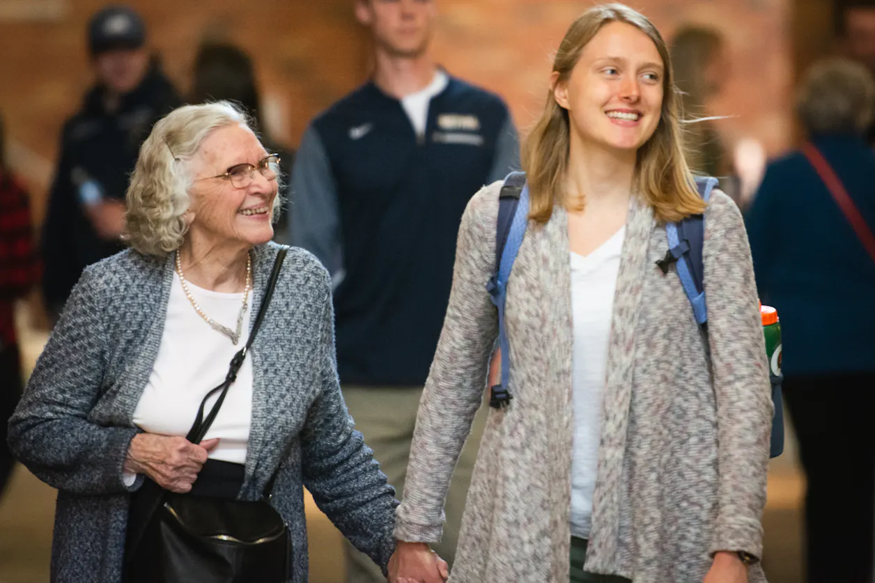 Student and grandparent hold hands in the hallway.