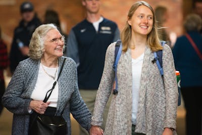 Student and grandparent hold hands in the hallway.