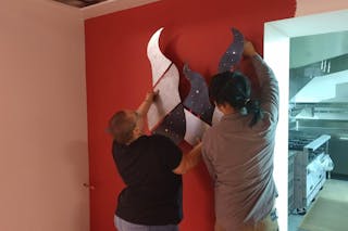 The student artist helps install the artwork at St. Matthew's