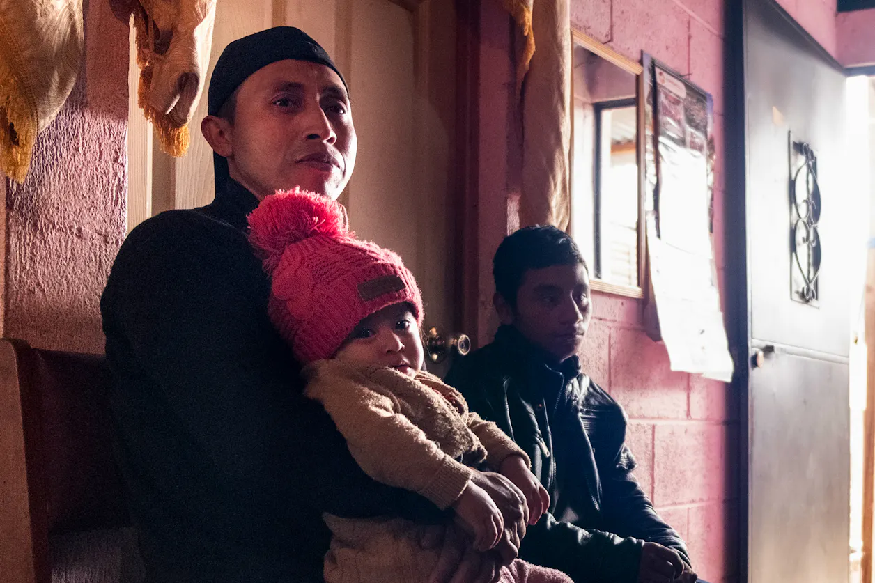 Mardoqueo Tian sits with his daughter, Ana Lucia, in the house they share with Tian’s parents in Tecpán, Guatemala. | Photo by Bryson Rosell