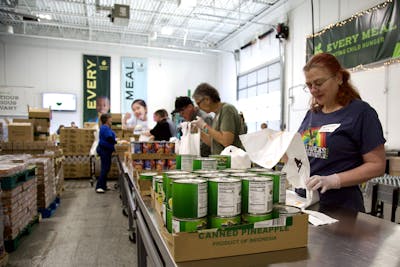 A team of volunteers pack canned food at Every Meal’s warehouse in Roseville, Minnesota. 