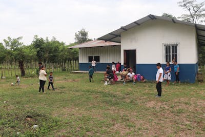 Students play outside a blue and white school building in Guatemala