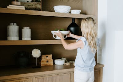 Alisa Sparks '08 carefully places a bowl on a shelf for a staged photo in a million dollar home.