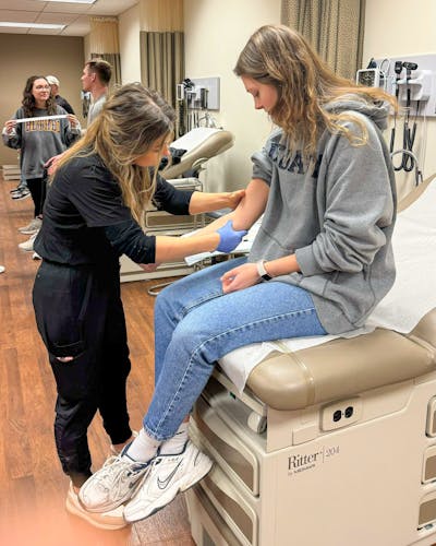 PA student draws blood for biochemistry undergrad student. 