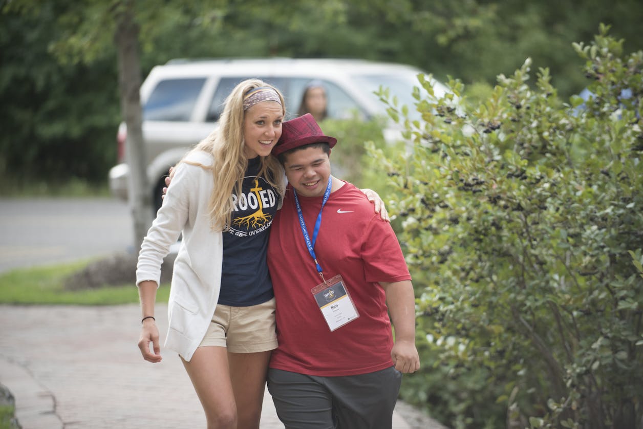 A friend walks arm-in-arm with a student in BUILD outside on campus.