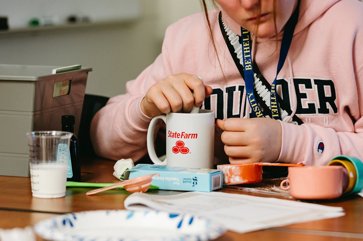 Student in BUILD stirs a mug during a hands-on cooking lesson with ingredients on the table.