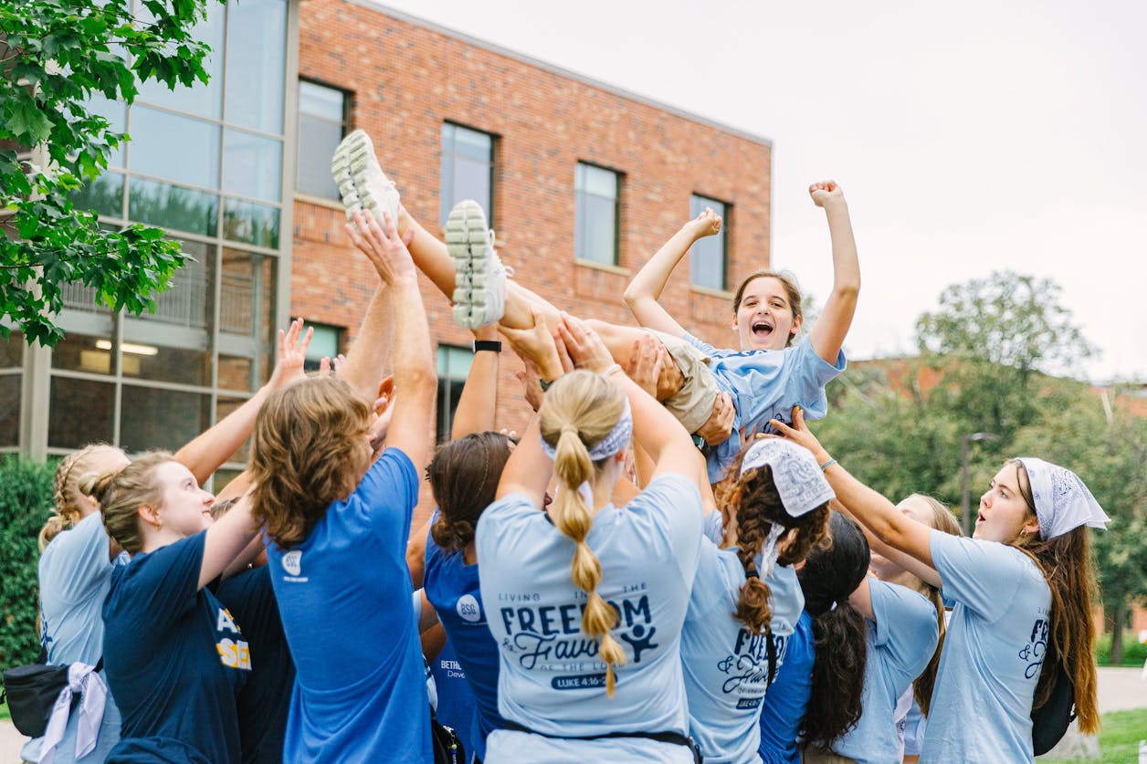 Student is lifted in the air by a cheering group outside Bethel University.