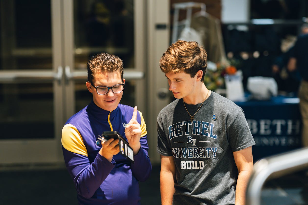 Two young men smile and look at a phone in a Bethel BUILD event space.