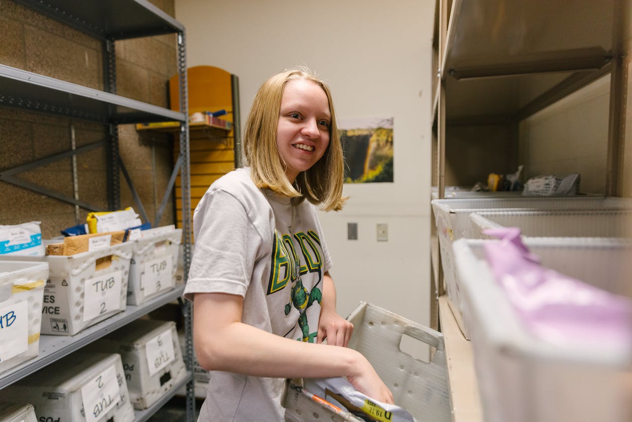 Student in BUILD sorts packages in a mailroom work experience.