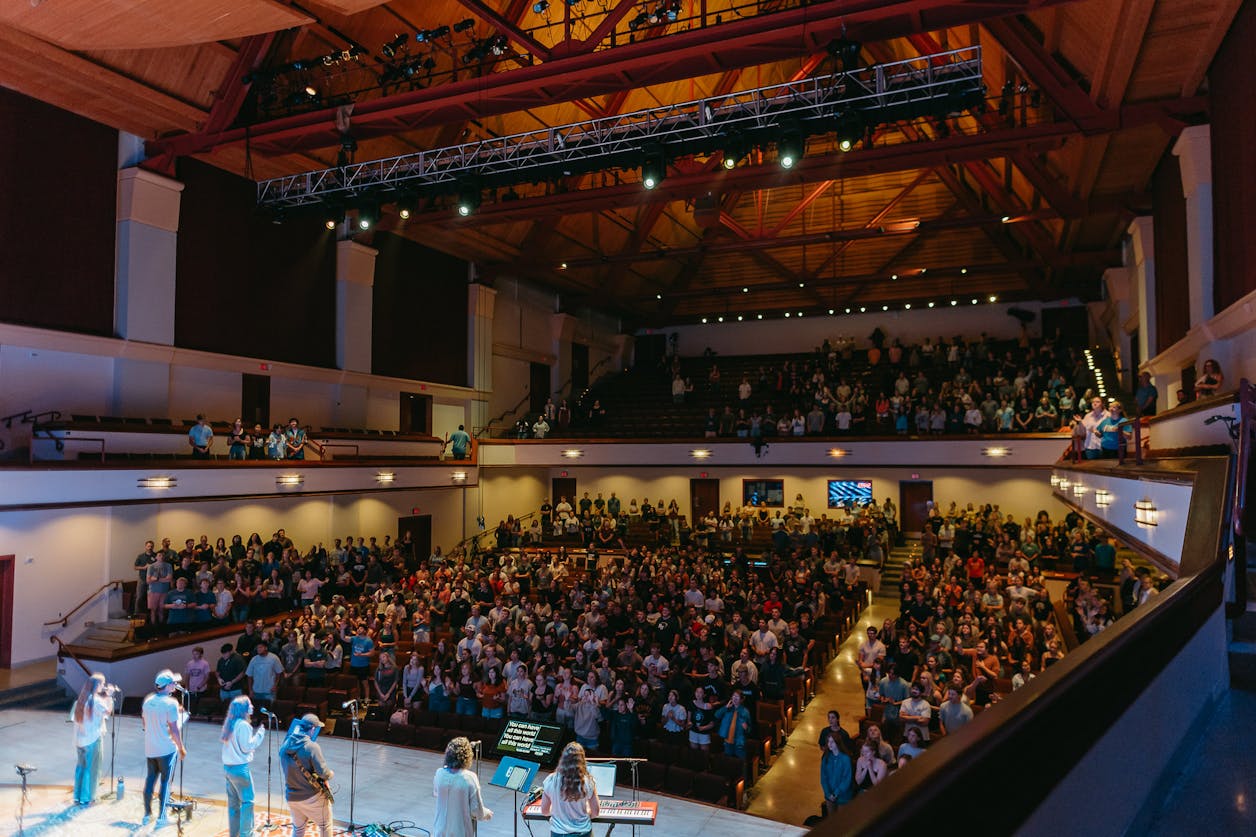 Full auditorium of students and a worship team onstage during chapel at Bethel. 