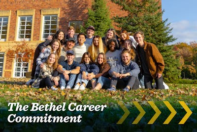 Group of smiling Bethel students posing together outside on a sunny fall day.