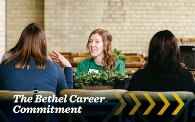 Three women sit talking around a table at a Bethel University career event.