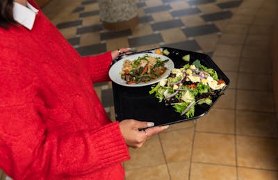 Student carries a tray of salad in the Dining Center