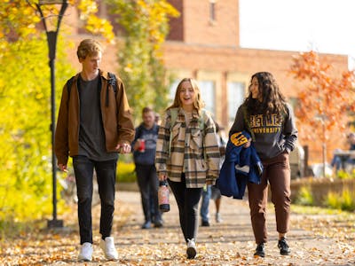 three students walking together in fall