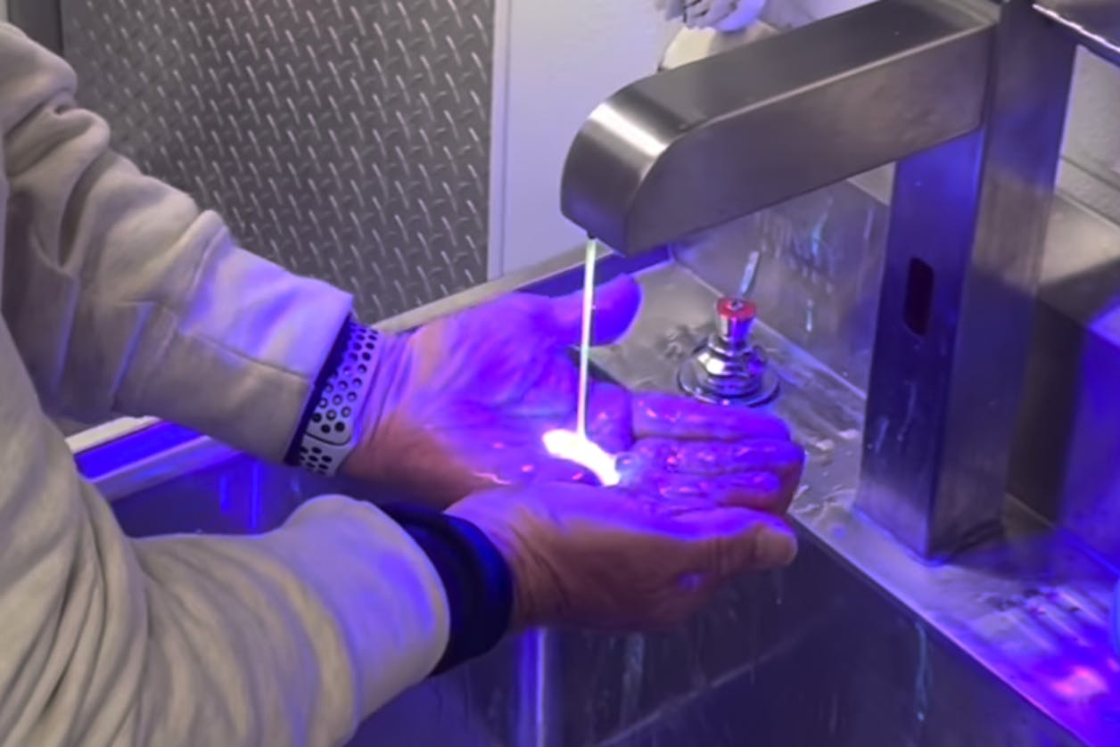 A scientist in Bethel's department of chemistry and biochemistry does a test wash under a faucet with a glowing black light