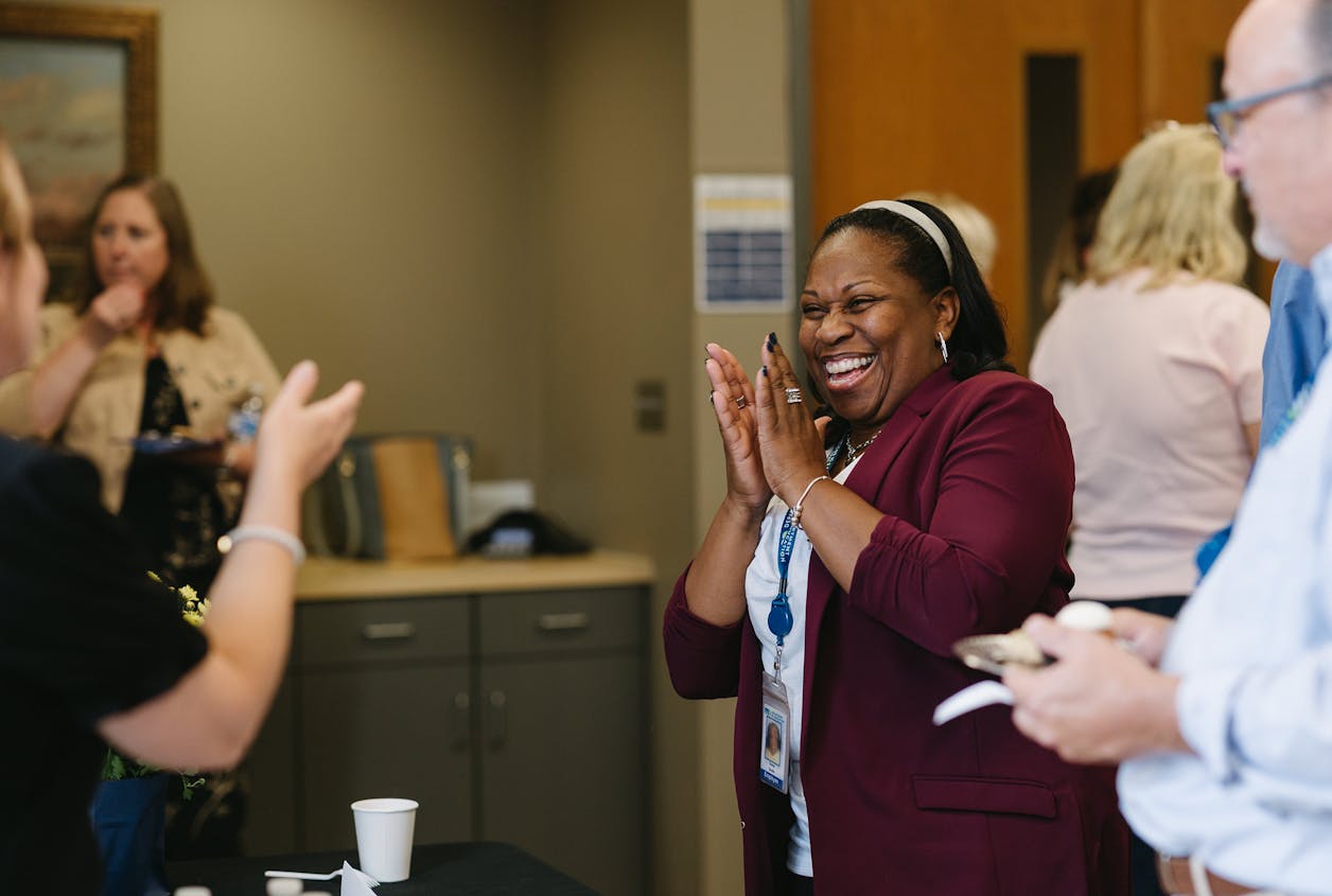 Woman claps and laughs with joy during a lively Bethel University event.