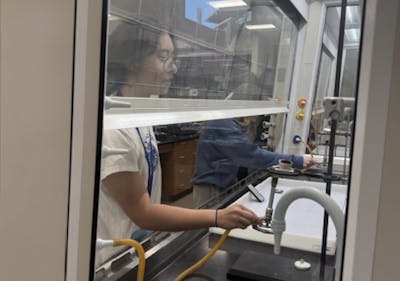Forensic Science Camp student conducts an experiment inside a fume hood at Bethel University.