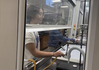 Forensic Science Camp student conducts an experiment inside a fume hood at Bethel University.