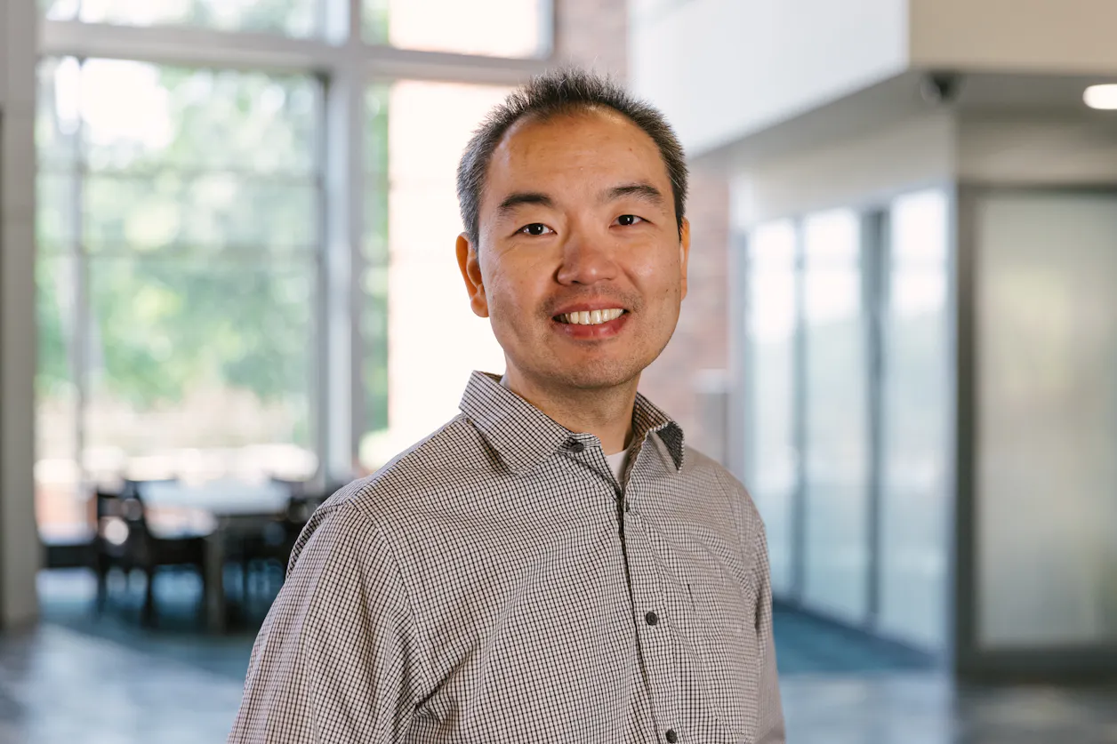 Professor Tao Wu smiles in the Brushaber Commons at Bethel. 