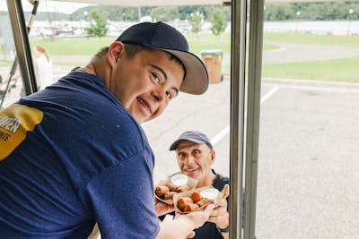 David serves taters to a customer out his food truck window