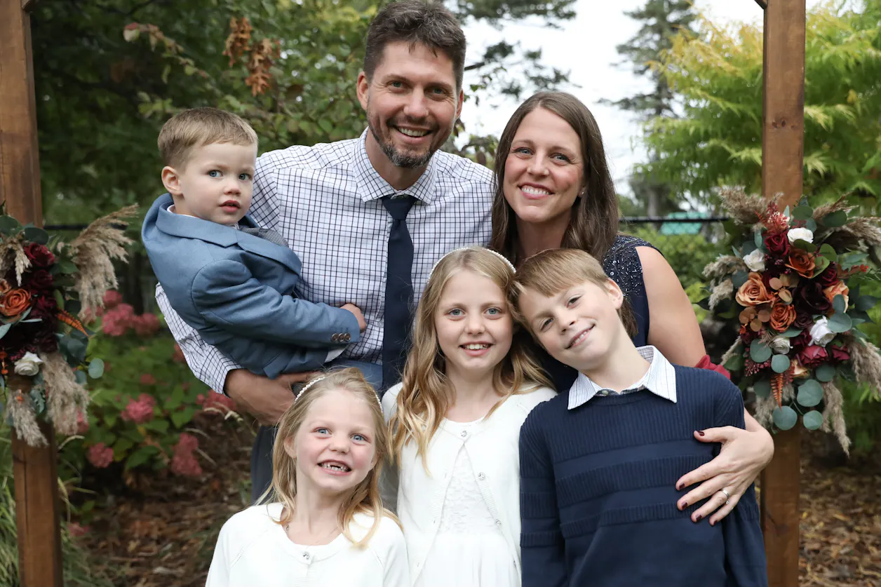 Tyler Moberg and his wife Jessica pose with their four children in a family photo.