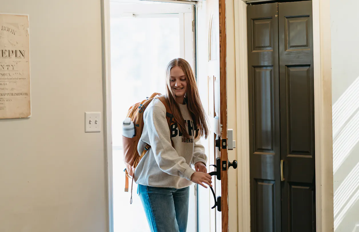 Student in a Bethel sweatshirt walks into their home