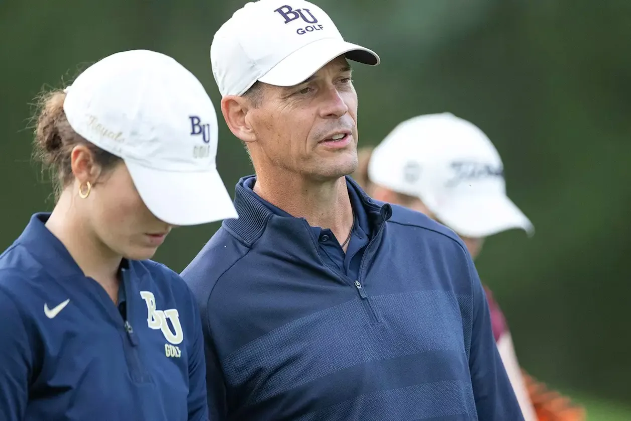Bethel golf coach talks with players during a collegiate golf tournament.
