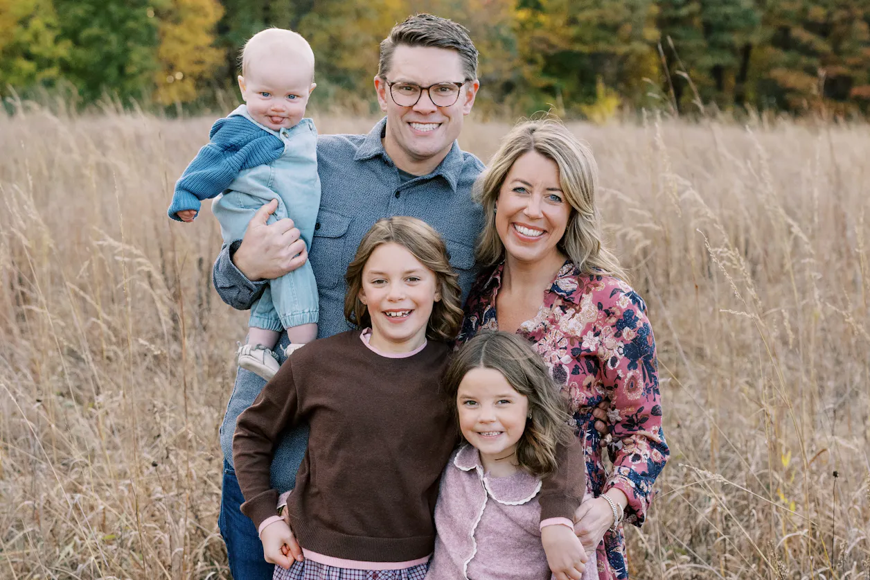 Angela Anderson ’11 GS’16 with her husband and Bethel graduate, Preston Anderson ’11, and their three children in a field posing for a family photo.