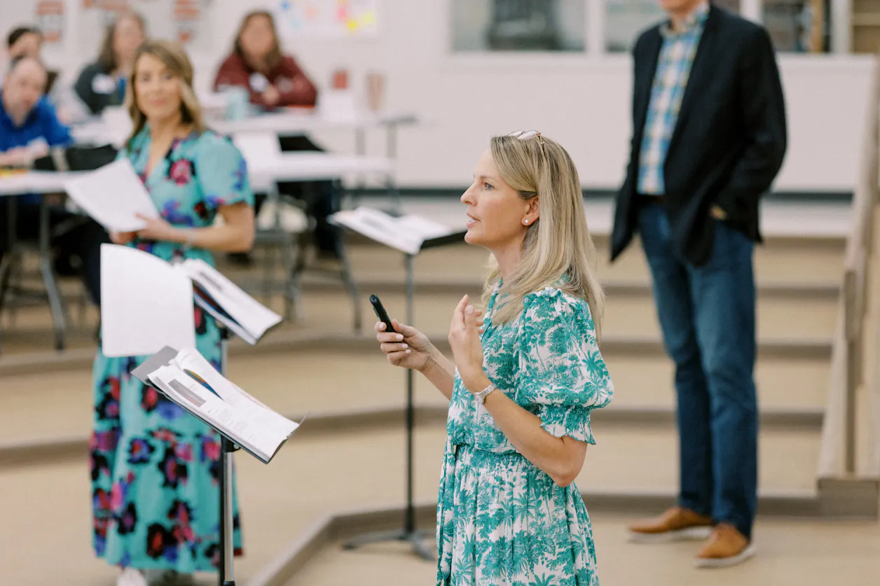 Amanda Kopischke leads educators through a large-group professional development session. She is holding a remote and speaking at the front of a classroom lecture hall. 