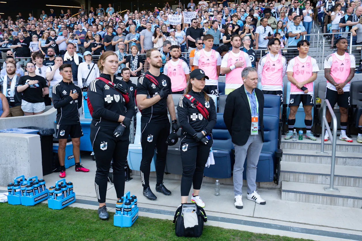 Minnesota United FC medical staff stand on the sideline during the national anthem before a match