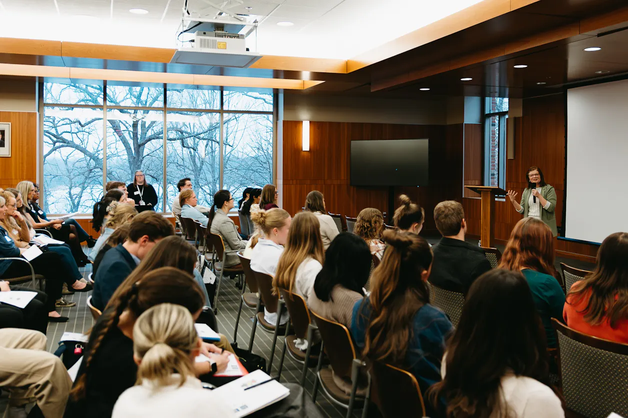 Krista Aadland ’03, S’12, GS’25 stands at the front of a room presenting at a Bethel Advance event