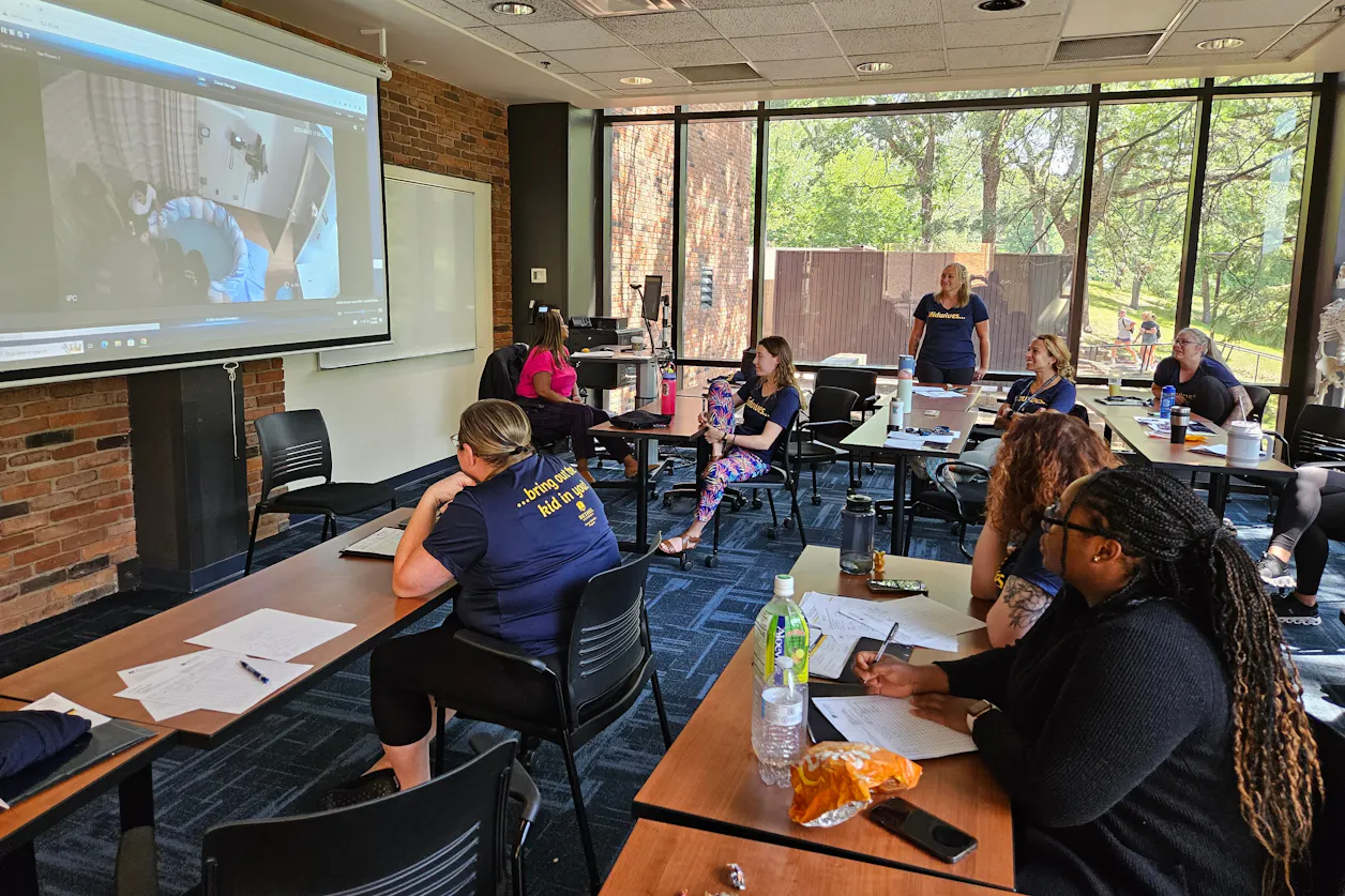 Students observe and discuss birth simulations from a nearby classroom.