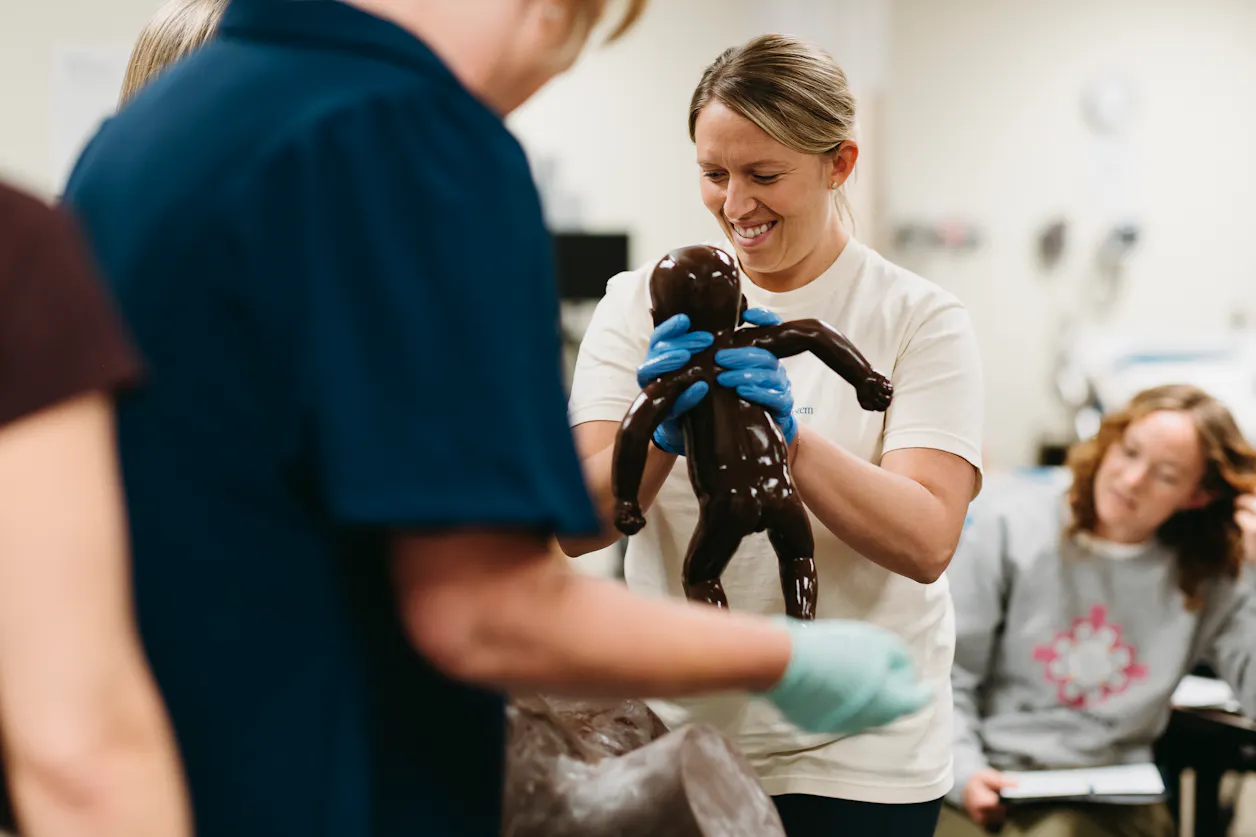 Students practice delivery maneuvers using a “Sophie and Her Mum” birth model