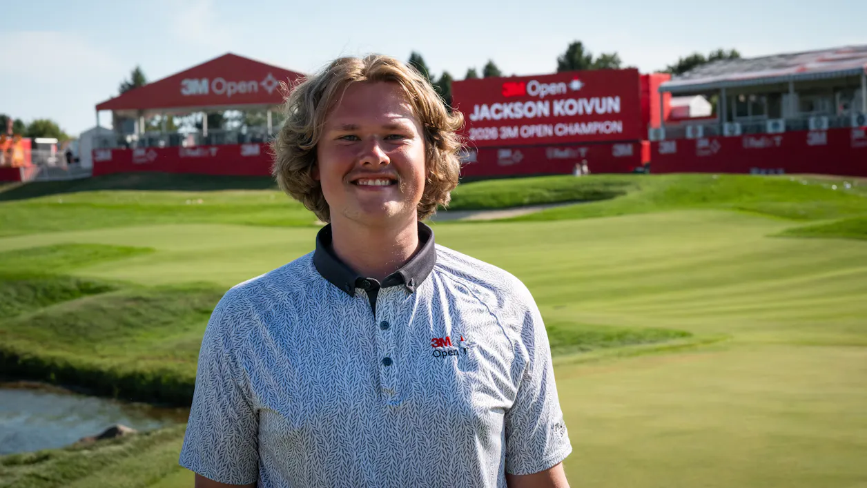 Bennett Moger smiles while standing near a golf hold of the 3M Open event. 