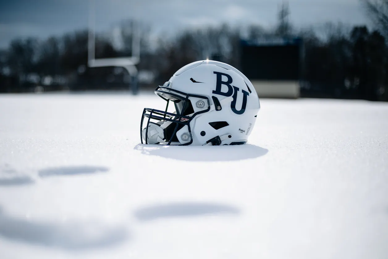 A white Bethel football helmet sits in the snow on the field. 