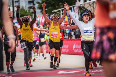 Runners complete the Chicago Marathon with their hands raised in excitement