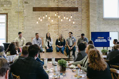 Panelists speak to alumni at a Bethel networking event in a warmly lit, modern space.