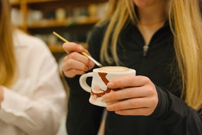 Close-up of a student painting a ceramic mug. 