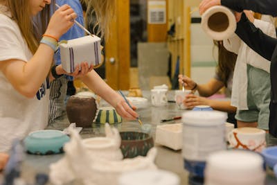 Students painting ceramics in a pottery studio. 