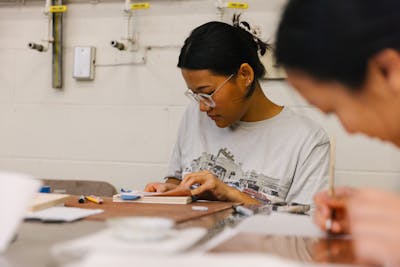 Art student deeply engrossed in a delicate painting project.